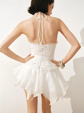 White dress with a halter neck and ruffled skirt on a plain background